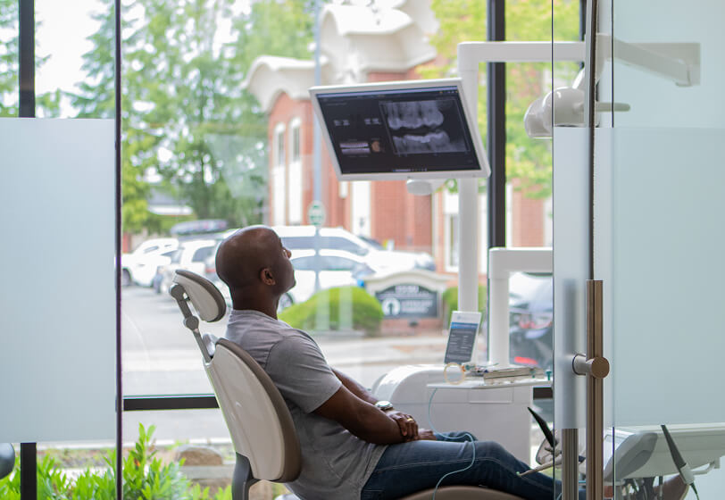 Dental patient sitting in dental chair looking at his x-rays